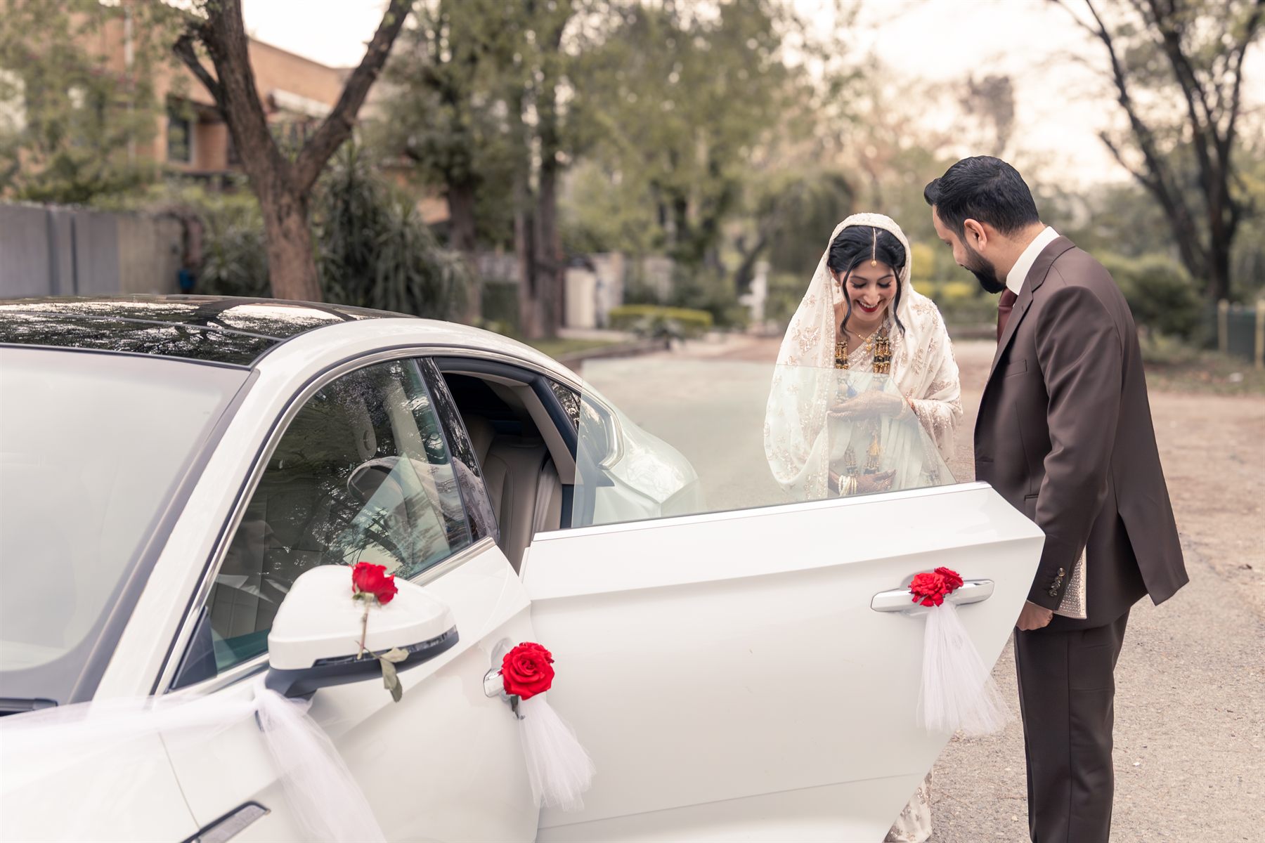 Bride and groom arriving beside a decorated wedding car