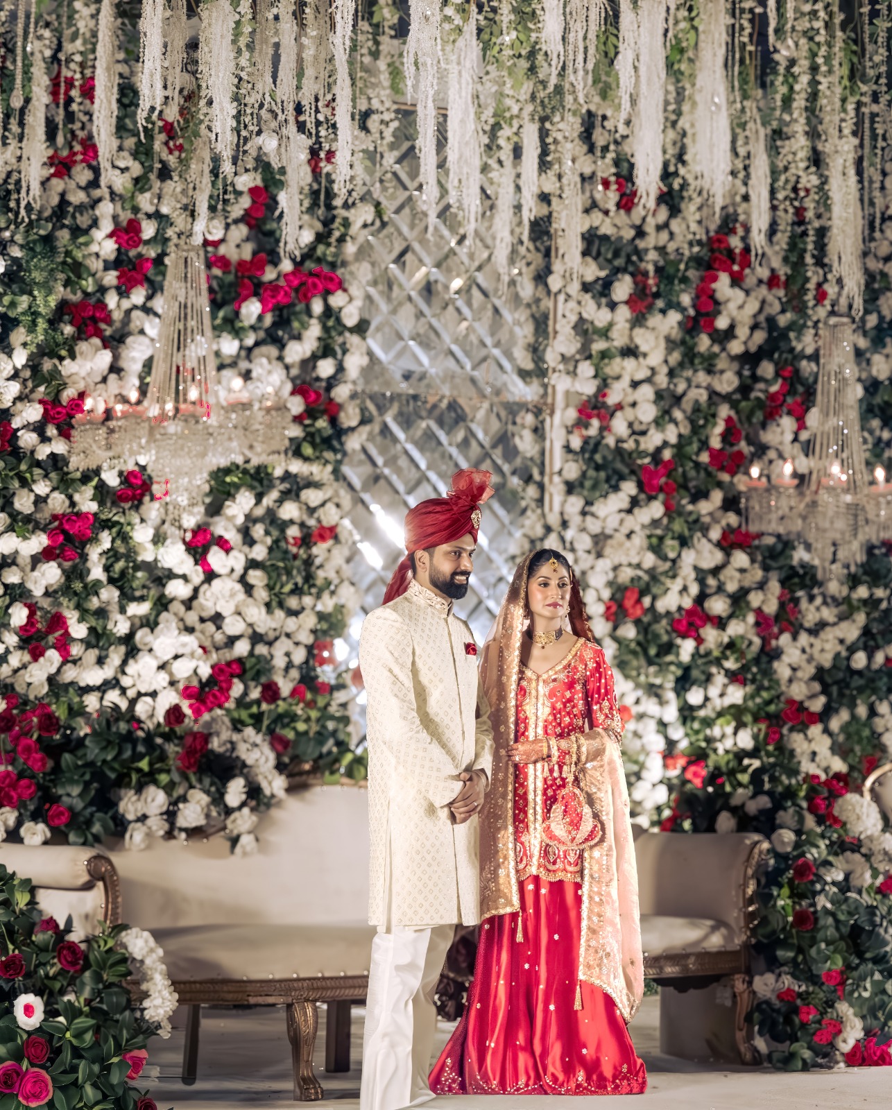 South Asian bride and groom in front of floral wedding decor